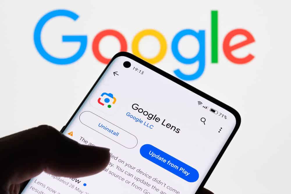 Zbliżenie ekranu smartfona wyświetlającego aplikację Google Lens z logo Google w tle